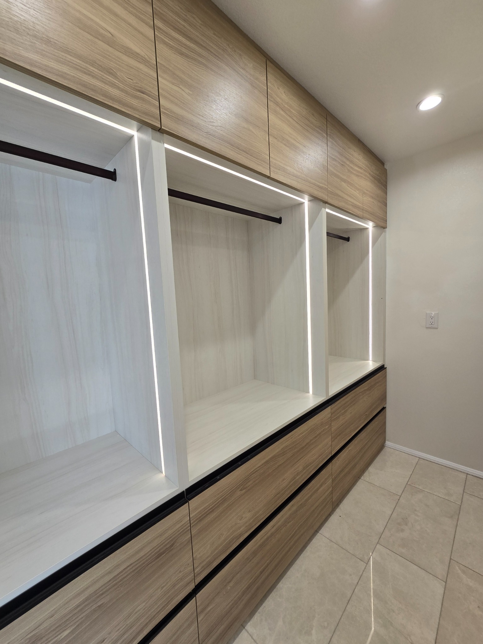 Custom closet bays with LED reveals and woodgrain drawers.