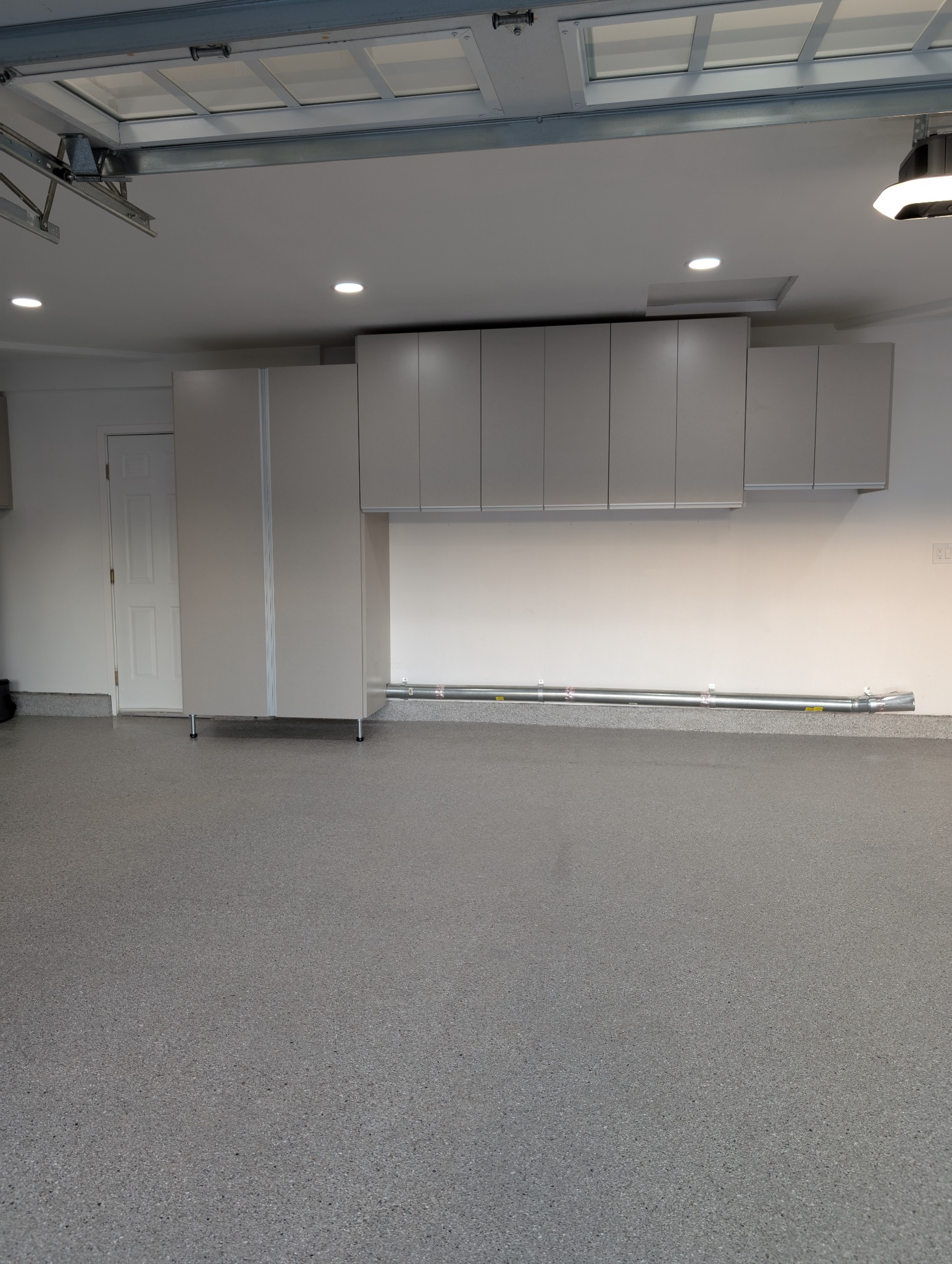 Wall-mounted garage cabinets with epoxy flooring.