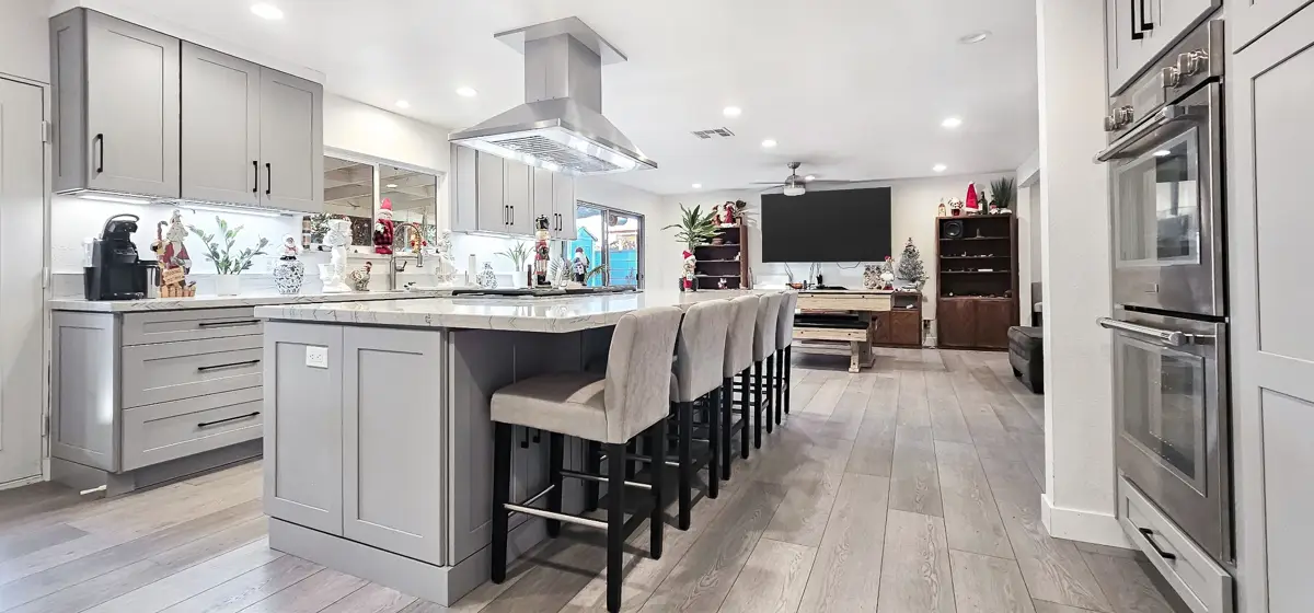 Gray kitchen island with bar stools open to living room