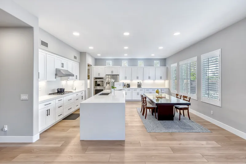Spacious white kitchen with island and dining table