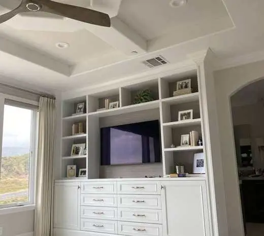 Custom white built-in with a TV niche, open display shelves, and drawer storage below