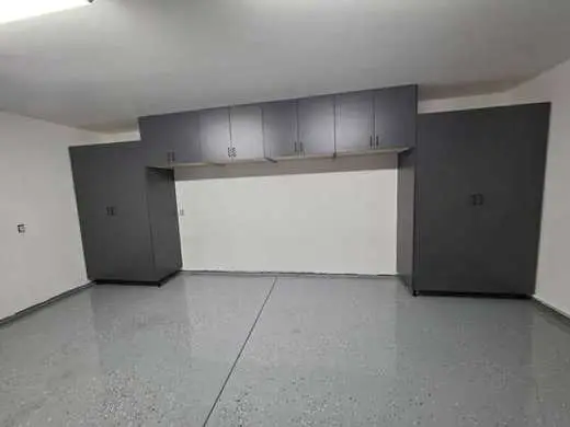 Custom charcoal-gray floor-to-ceiling garage cabinets with an epoxy flake floor
