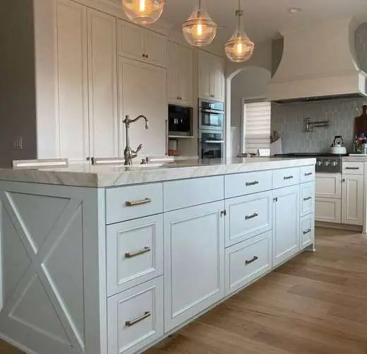 Custom white kitchen cabinets with a marble-look island, farmhouse sink, and brushed nickel hardware