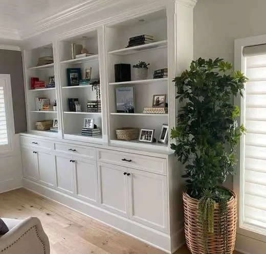 Custom white built-in bookcase with open shelving, cabinet storage below, and black hardware