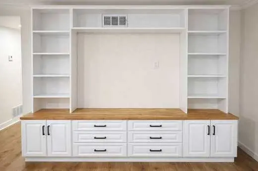 Custom white entertainment center with a TV niche, open shelves, and black hardware