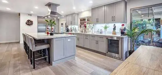 Custom light gray Shaker kitchen cabinets with a marble-look island and pendant lighting