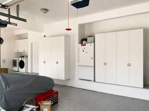 Custom white garage cabinets built above and around a washer and dryer