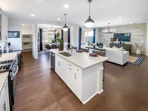 Custom white Shaker kitchen with quartz countertops, brushed nickel hardware, and an open-plan layout into the living room