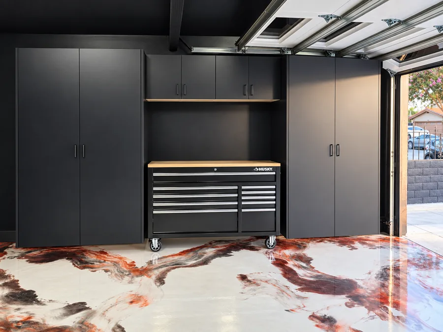 Custom matte black garage cabinets with tall storage, wall cabinets, and a workbench bay over a metallic epoxy floor